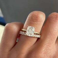 a woman's hand with a diamond ring on top of her finger and the other hand holding an engagement ring