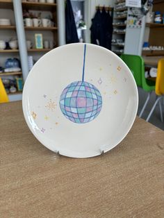 a white plate with a blue and pink design on it sitting on a wooden table