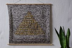 a wall hanging with a yellow christmas tree on it next to a potted plant