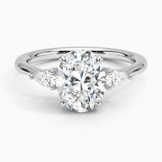 an oval cut diamond ring with three diamonds on the band and side stones set in 18k white gold