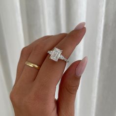 a woman's hand with a diamond ring on top of her finger and an engagement band