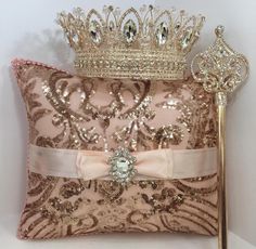 a pink pillow with a tiara on top and a gold stick in the middle