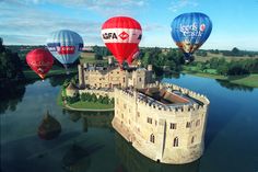 several hot air balloons flying over a castle