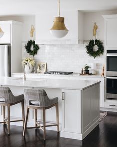 an instagram page with two chairs in front of a kitchen island and white cabinets