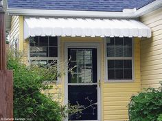 a yellow house with a black door and white awning