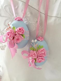 two ornaments with pink roses on them are hanging