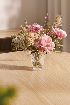 a vase filled with pink flowers on top of a wooden table