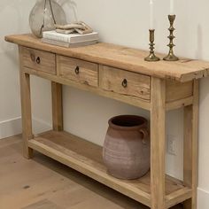 a wooden table with two vases on top of it next to a candle holder