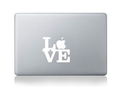 an apple laptop with the word love on it's back and black letters that spell i love