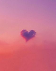 a heart - shaped cloud in the sky at sunset, with pink and purple hues