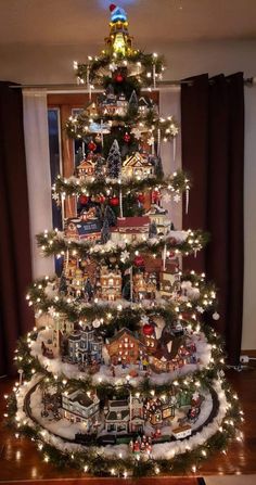 a christmas tree is decorated with lights and houses in the shape of train tracks on it