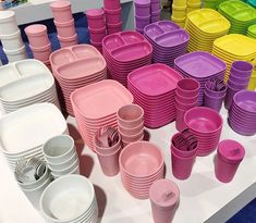 a table topped with lots of different colored plates and cups