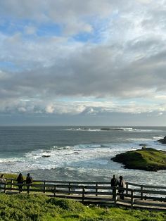 people standing on a fence looking out at the ocean