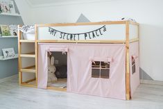 a child's bedroom with a pink tent bed and shelves on the wall next to it