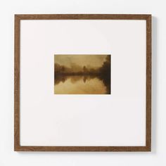 a painting hanging on the wall above a white frame with a brown border around it