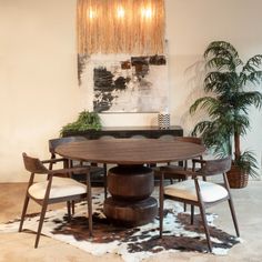 a dining room table with four chairs and a cow hide rug on the floor in front of it