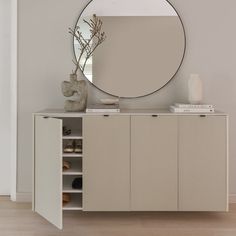 a white cabinet with a round mirror above it