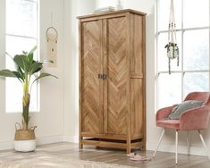 a wooden cabinet sitting next to a pink chair in a living room with white walls