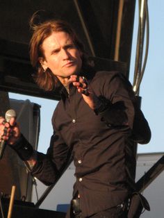 a man holding a microphone in his right hand and standing next to him on stage