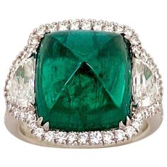 an emerald and diamond ring with diamonds around it