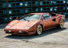 an orange sports car parked in front of stacks of crates