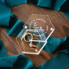 an acrylic box with two rings on it and some blue fabric around it