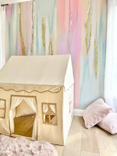 a white tent sitting on top of a hard wood floor next to a pink and blue wall