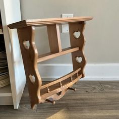 a wooden shelf with hearts cut out of the front and sides, on top of a hard wood floor