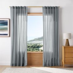 the curtains are open and ready to be hung in front of the window with an ocean view