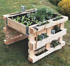 a wooden planter filled with lots of plants on top of a grass covered field