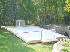 an outdoor basketball court in the middle of a yard with a goal on it and some trees