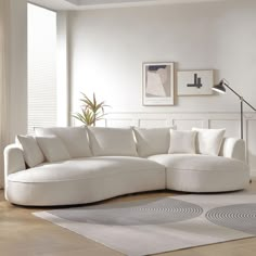 a living room with a large white sectional couch and rugs on the hardwood floor