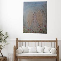 an angel painting hanging on the wall above a white couch in a room with wooden furniture