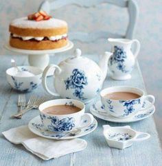 a table topped with cups and saucers next to a cake on top of a plate