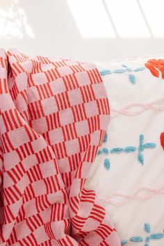 a red and white pillow sitting on top of a bed