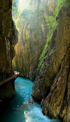 a river flowing through a canyon next to a bridge