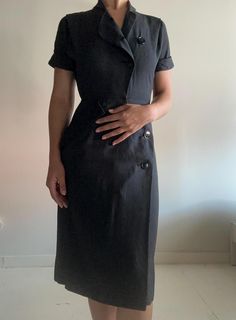 This dress is classic, and it has a beautiful fit. I sourced this is San Francisco. It's in perfect condition, not a button out of place. I believe the dress is 100% cotton. Please reach out with any questions.  Measurements Shoulder: 14 inches Sleeve length: 7 inches  Waist: 13 inches Hip: 18.5 inches Length: 42 inches Bottom opening: 22 inches PLEASE READ MEASUREMENTS *All items are measured flat. Measurements are not doubled.* EXCHANGE/STORE CREDIT ONLY Please view return policy DISCLOSURE Some items have been professionally cleaned and altered. Photos and measurements reflect the current state of the item. All additional care is the responsibility of the buyer. Black Dress With Side Buttons For Work, Black Dresses With Side Buttons For Work, Black Workwear Dress With Side Buttons, Fitted Knee-length Dresses With Buttons, Classic Knee-length Vintage Dress For Work, Elegant Short Sleeve Shirt Dress With Buttons, Fitted Vintage Dress For Semi-formal Occasions, Fitted Sheath Dress With Buttons, Vintage Fitted Office Dress