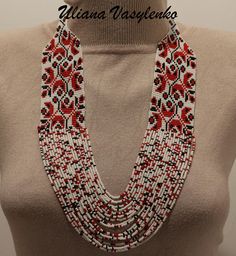 a woman wearing a red and white beaded necklace on top of a mannequin