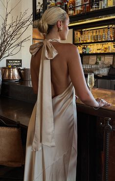 a woman in a dress standing at a bar with her back turned to the camera