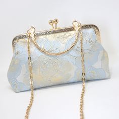 New to our Millennium collection, This beautiful romantic Light Blue Shimmering Gold Rose FLORAL bridal clutch bag is made of very fine quality of fabric and metal and it comes with a long Detachable metal chain for your Big day! Dimensions- length oh the bag is 5.5 inches and width of the bag is 9 inches. Gold Metal chain about 44 inches long. ► ABOUT YOUR ORDER * All items are neatly packaged in our beautiful jewelry boxes and elegant organza bags. * All items are 100% gift-ready. * Each order comes with a personalized handwritten card and a branded Millennium Bride jewelry cloth. * Each order comes with a free gift. ► PERSONALIZTION * If your order is a gift, you may contact us with the recipient's name or a message, and we'll print a personalized card that will be elegantly packaged wi Gold Evening Bag With Detachable Strap For Wedding, Luxury Wedding Bag With Detachable Strap, Elegant Blue Shoulder Bag For Wedding, Elegant Wedding Shoulder Bag With Detachable Strap, Gold Clutch With Detachable Handle For Wedding, Elegant Pouch Bag For Ceremony, Wedding Clutch With Detachable Strap, Elegant Pouch Bag For Ceremonies, Elegant Rectangular Clutch For Mother Of The Bride