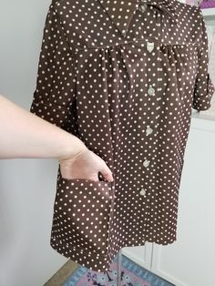 "Cute little polka dot blouse! Made from poly knit, this blouse buttons down the front and has two patch pockets. The front gathers softly into the yoke and has a collared neckline. Label reads, \"Tara One\" Good to fair vintage condition. There are some picks/pulls on the upper back, and a popped section of seam on one sleeve cuff Measurements Bust: Up to 43\" Length: 26\" Size Large" Polka Dot Blouse With Button Closure For Workwear, Vintage Short Sleeve Blouse With Pockets, Polka Dot Collared Blouse With Button Closure, Brown Button Closure Blouse For Daywear, Brown Blouse With Button Closure For Daywear, Vintage Collared Blouse With Placket, Polka Dot Cotton Blouse With Button Closure, Collared Brown Blouse For Daywear, Brown Collared Blouse For Daywear