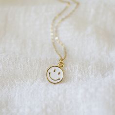 "Beautiful and lovely tiny happy face charm necklace. Made of white enamel gold smiley face charm with skinny gold plated brass chain. Soft and warm. Great for gift , everyday or special occasion. Your item will ship in a gift box. Please feel free to contact me if you have any question. ♥ Length 14\" -20\" chain ♥ Charm 3/8\" ♥ Gold plated over brass / white enamel ♥ Delivery Time Fast shipping within 1 - 3 days ♥ See more Rudiana Accessories Rudiana.etsy.com" Cute Everyday White Necklace, Cute White Everyday Necklace, Cute White Nickel Free Necklaces, Cute White Nickel-free Necklaces, White Charm Necklace With Adjustable Chain As Gift, Cute White Nickel-free Charm Necklaces, Minimalist White Charm Necklaces, White Minimalist Charm Necklace, Minimalist White Charm Necklace