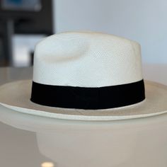 Sombrero Fino confeccionado en Cuenca Te presentamos con gran orgullo nuestro sombrero hecho en Cuenca, una auténtica obra maestra creada con esmero y dedicación por talentosos artesanos de la zona. Cada sombrero es el resultado de un delicado proceso completamente hecho a mano, lo que lo convierte en una verdadera pieza de arte y tradición. Únete a nosotros y descubre la belleza de nuestro sombrero tejido en Cuenca, una prenda con alma y corazón, creada con pasión por los talentosos artesanos l Elegant White Fedora With Flat Crown, Formal Wide Brim Hat In Natural Color, Elegant Flat Brim Toquilla Straw Hat, Elegant White Hat With Flat Crown, Luxury Fedora With Curved Brim In Toquilla Straw, Elegant White Panama Hat In Toquilla Straw, Elegant Toquilla Straw Hat With Curved Brim, Elegant Adjustable Toquilla Straw Hat, Elegant Natural Fedora Hats