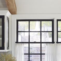 a kitchen window with black and white curtains