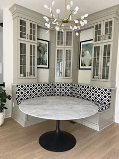 a large white table sitting under a chandelier in a room with gray cabinets