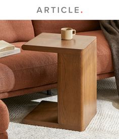 a wooden table sitting on top of a carpeted floor next to a brown couch