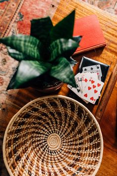 a basket with playing cards on it next to a potted plant and other items