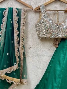 A three-piece emerald green mirror lehenga set from the Priti Sahni collection. This beautiful raw silk emerald green lehenga with a sari zari border detail is paired with a nude mirror blouse in pearl, and zardozi hand embroidery. This outfit is completed with an emerald green mirror work net dupatta with scalloped edging. Emerald Green Lehenga, Designer Lehnga Choli, Raw Silk Blouse, Mirror Work Lehenga, Raw Silk Lehenga, Lehenga Designs Simple, Green Lehenga, Green Mirrors, Silk Lehenga