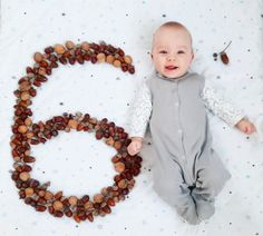 a baby laying on top of a blanket next to a number six made out of nuts