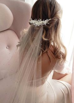 a woman in a wedding dress sitting on a couch with a veil over her head